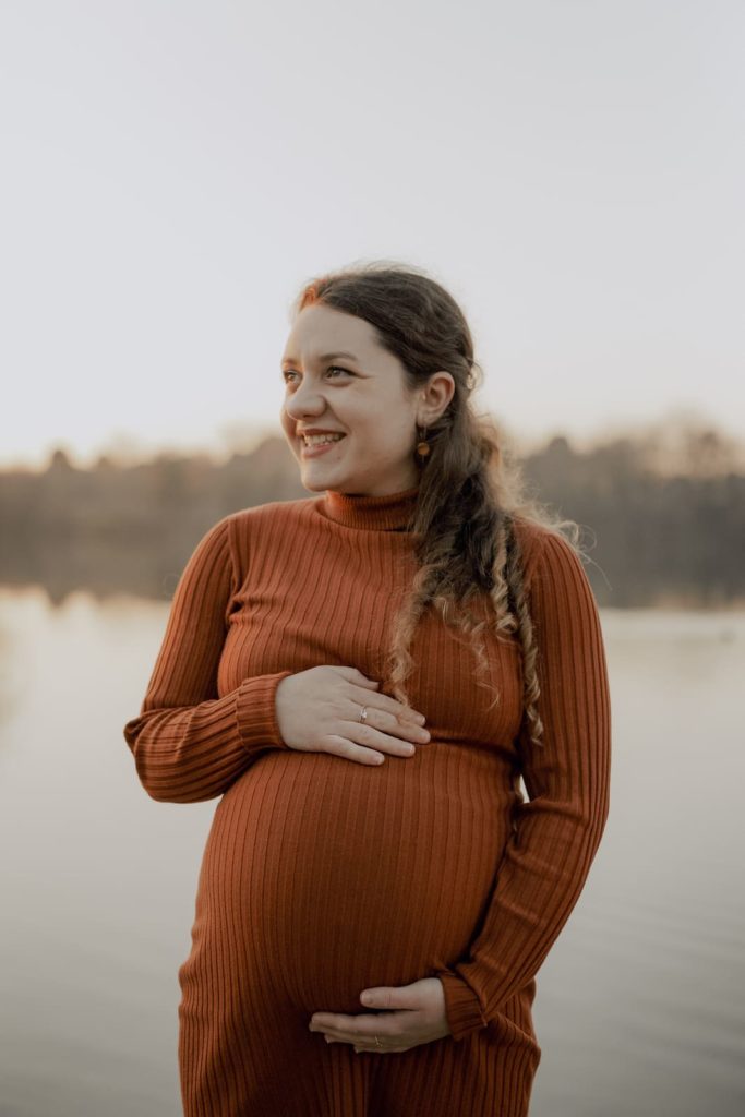 portrait d'une femme enceinte souriante portant une robe terracotta